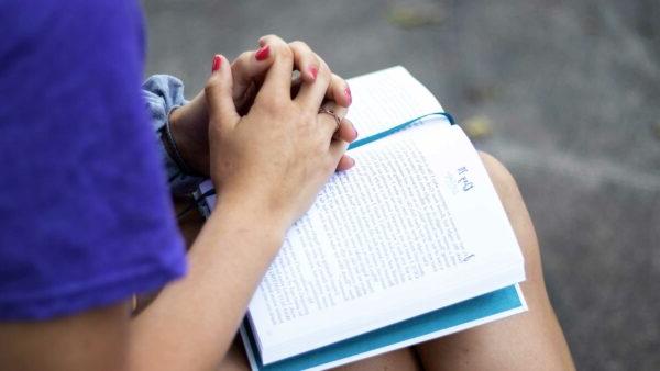 Student sitting with book outside